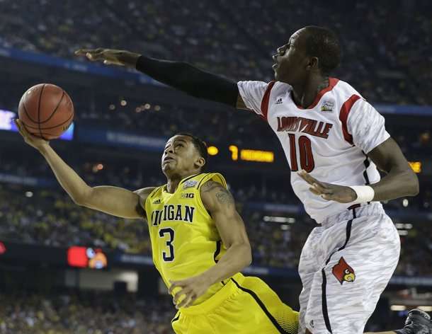 Michigan guard Trey Burke (3) shoots against Louisville center Gorgui Dieng (10) during the first half of the NCAA Final Four tournament college basketball championship game Monday, April 8, 2013, in Atlanta. (AP Photo/David J. Phillip)