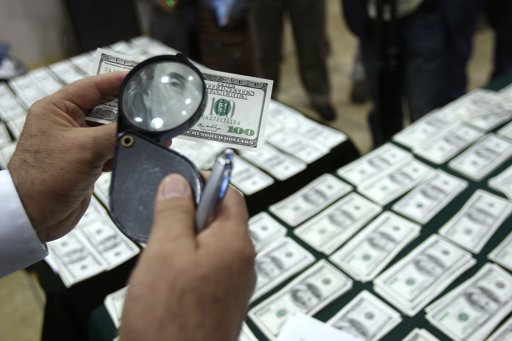 Un detective inspecciona un billete de 100 dólares que se cree es falso en Lima el 17 de agosto del 2013.