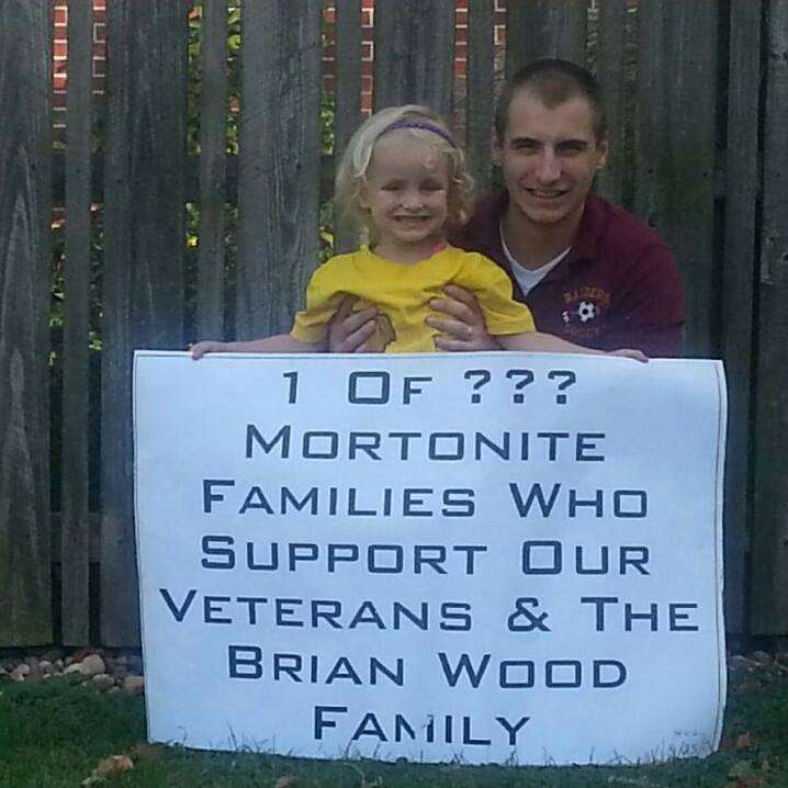 Zac Sorensen and his daughter hold a sign in
support of the Habitat for Humanity house for
the Wood family.