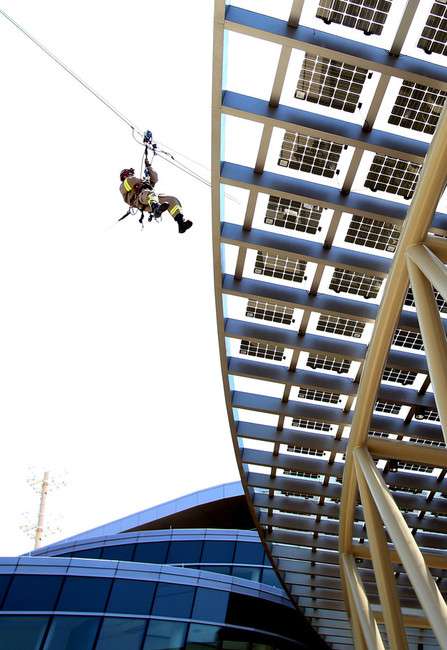 Firefighter Jason Buhler of Station 5's Heavy
Rescue Team transports the scissors for the
ribbon cutting via zip line during the grand
opening of the Public Safety Building in Salt
Lake City on Friday, July 19, 2013.