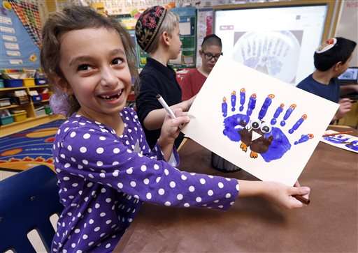 Second-grader Rozie Aronov, 7, holds up a
menurkey, a paper-and-paint mashup of a menorah
and turkey she created at Hillel Day School in
Farmington Hills, Mich., Wednesday, Nov. 20,
2013. (AP Photo/Paul Sancya)