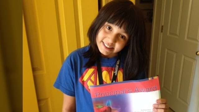 Katarina shows off her good grades at home.
Throughout most of elementary school, she wore
a wig to hide her baldness, caused by her
alopecia.