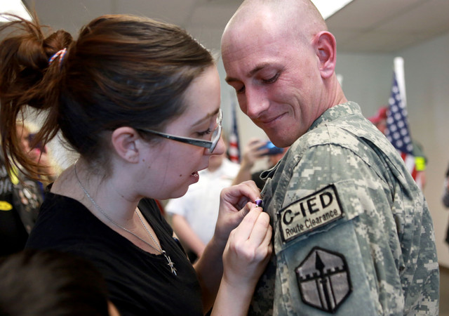 Julie McCloy helps her husband Spc. James McCloy attach his Purple 
Heart pin after he was awarded it for injuries he sustained during his 
deployment to Afghanistan in 2011 at the office of Utah 
Congressman Chris Stewart in Salt Lake City on Thursday, March 20, 
2014.
