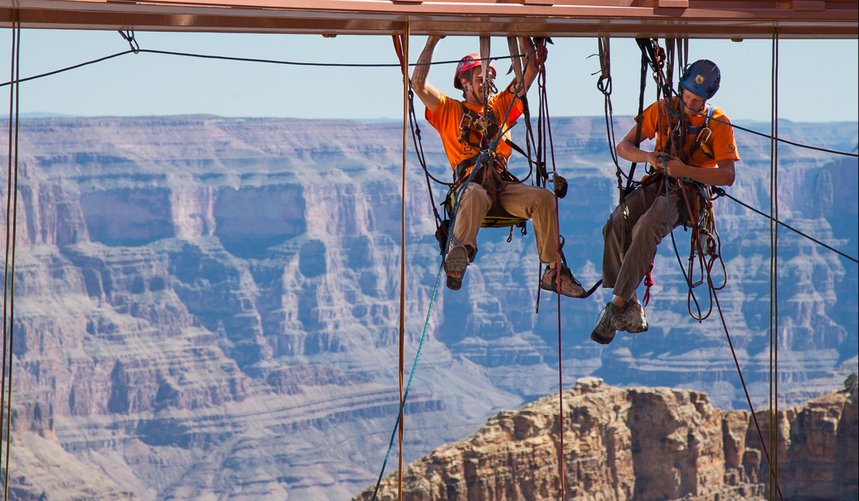Workers dangle from ropes to clean Skywalk glass