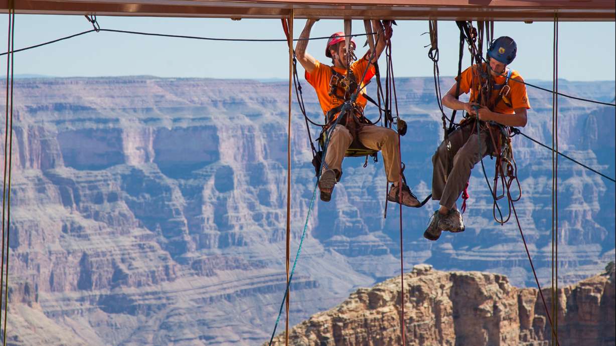 Workers dangle from ropes to clean Skywalk glass