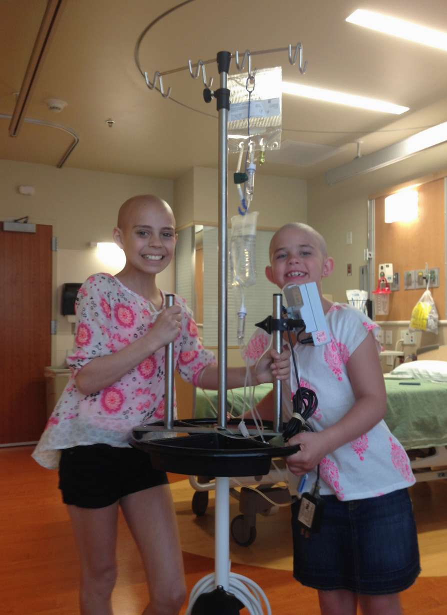In this 2014 photo provided by their families,
Delaney Clements, 11, left, and Kamryn Renfro,
9, right, stand together at a hospital in
Colorado. Kamryn was suspended from her public
charter school in Grand Junction because a
shaved head goes against the school's dress
code. But the school quickly reversed the
decision.