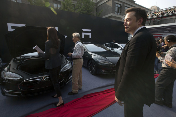 Tesla Motors CEO Elon Musk looks on as eight Tesla Model S electric sedans are delivered to its first customers in China at an event in Beijing, China, on Tuesday.