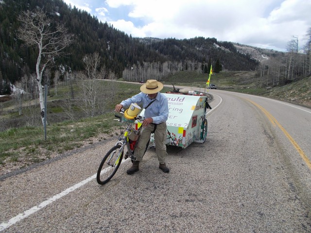 David "Cannonball" Smith, 72, pushes his
bicycle and trailer up a hill while on a
journey from Utah to South Carolina. He hopes
to spread "compassion and sharing" during the
trip, which began on May 12, 2014.