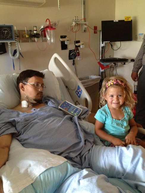 Jared Maynes lays beside his daughter during a hospital stay.