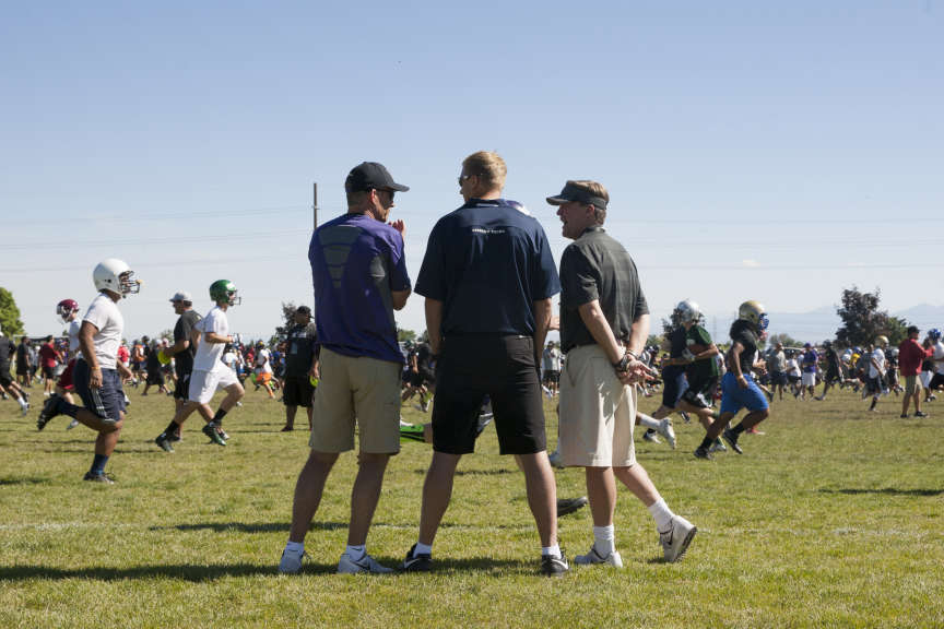 University of Colorado Head Coach Mike
MacIntyre, right, talks with University of
Washington Head Coach Chris Petersen, left, and
BYU Head Coach Bronco Mendenhall, center, as
players run warm-ups during the All Poly high
school football camp at Ellison Park.