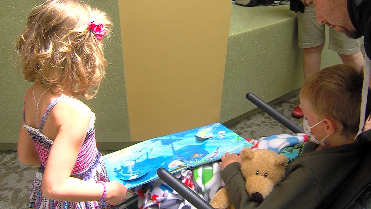 Abigail Walsh (left) reads a book with a boy at Primary Children's
Hospital. Abigail requested books for her birthday so that she could
donate them.