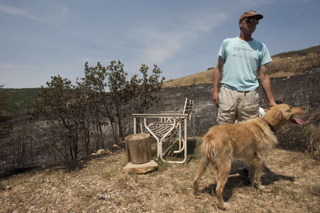 Larry Fry pets his dog, Bojangles, at his home at 299 Park View Lane after a fire burned about 120 acres near the Rockport Estates community in Wanship, Saturday, July 26, 2014.