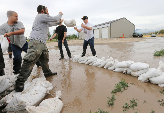 Eagle Mountain residents and city employees work Tuesday, July 29, 2014, to lay sandbags and help out after heavy rain caused flooding in portions of the area.
