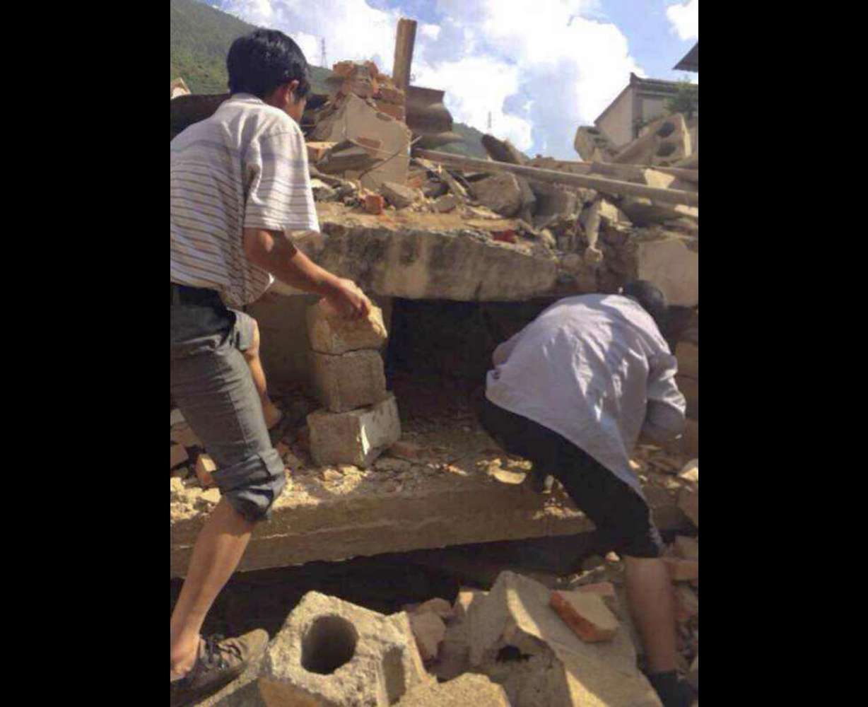 In this photo taken by cellphone and released by China's Xinhua News Agency, men at rubbles of buildings look for survivors after an earthquake in Ludian County of Zhaotong City in southwest China's Yunnan Province Sunday, Aug. 3, 2014. A strong earthquake rattled southwest China on Sunday, knocking out communication and power lines and causing people to rush out of buildings, but there were no immediate reports of injuries.