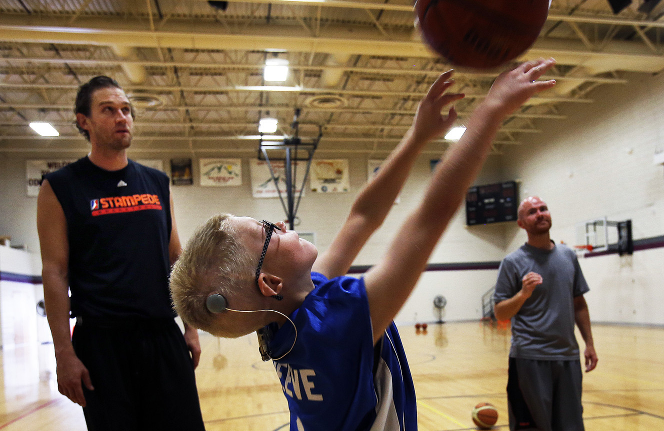 Hayden Reeve takes a shot during a basketball clinic for deaf and hearing impaired children, their siblings, and youths with disabilities at the Sanderson Community Center of the Deaf and Hard of Hearing in Taylorsville, Monday, Aug. 4, 2014. At back left is Lance Allred. At right is Clay Anderson.