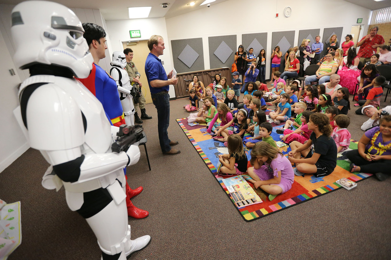 Salt Lake County Mayor Ben McAdams reads to a group of kids Friday, Aug. 8, 2014, as the Kearns Library celebrates 50 years with games, superheroes, story time, a bounce house and fun for the kids.