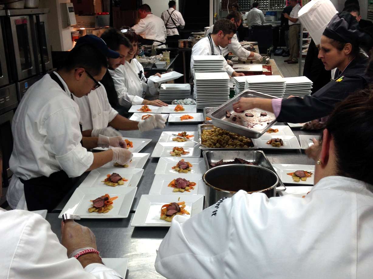 In this Sept. 26 2013 photo, staff members prepare dishes of slow-cooked beef served with gnocchi fashioned out of McDonald's french fries and a fruit sauce from its smoothie mix during a dinner hosted by McDonald's for reporters and bloggers, in New York.