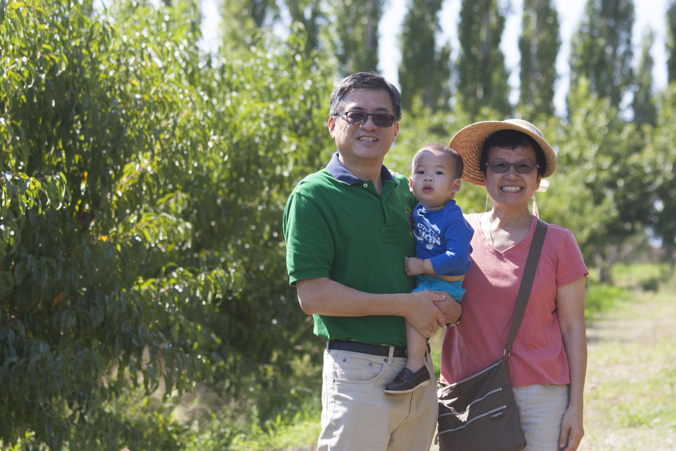 Andy and Eleanor, of Springville, picking peaches with their grandchild.