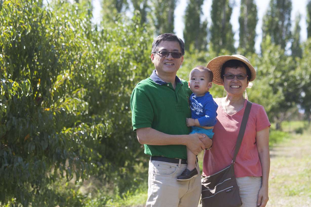 Andy and Eleanor, of Springville, picking peaches with their grandchild.