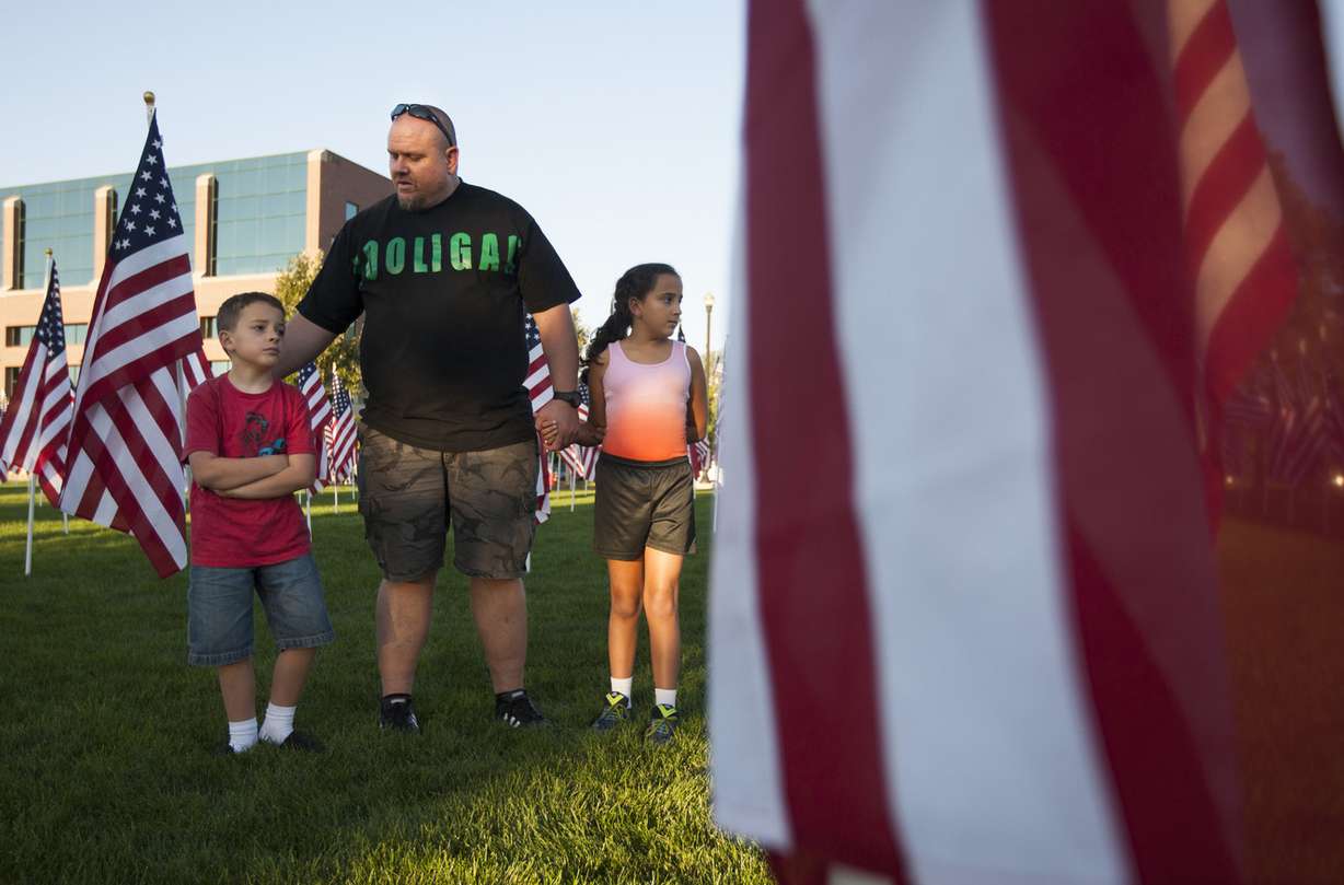 Sean Phillips talks to Racer Phillips, 8, left, and Rain Phillips, 10, right, about the importance of the flags at the 13th annual Utah Healing Field in Sandy on Wednesday, Sept. 10, 2014.