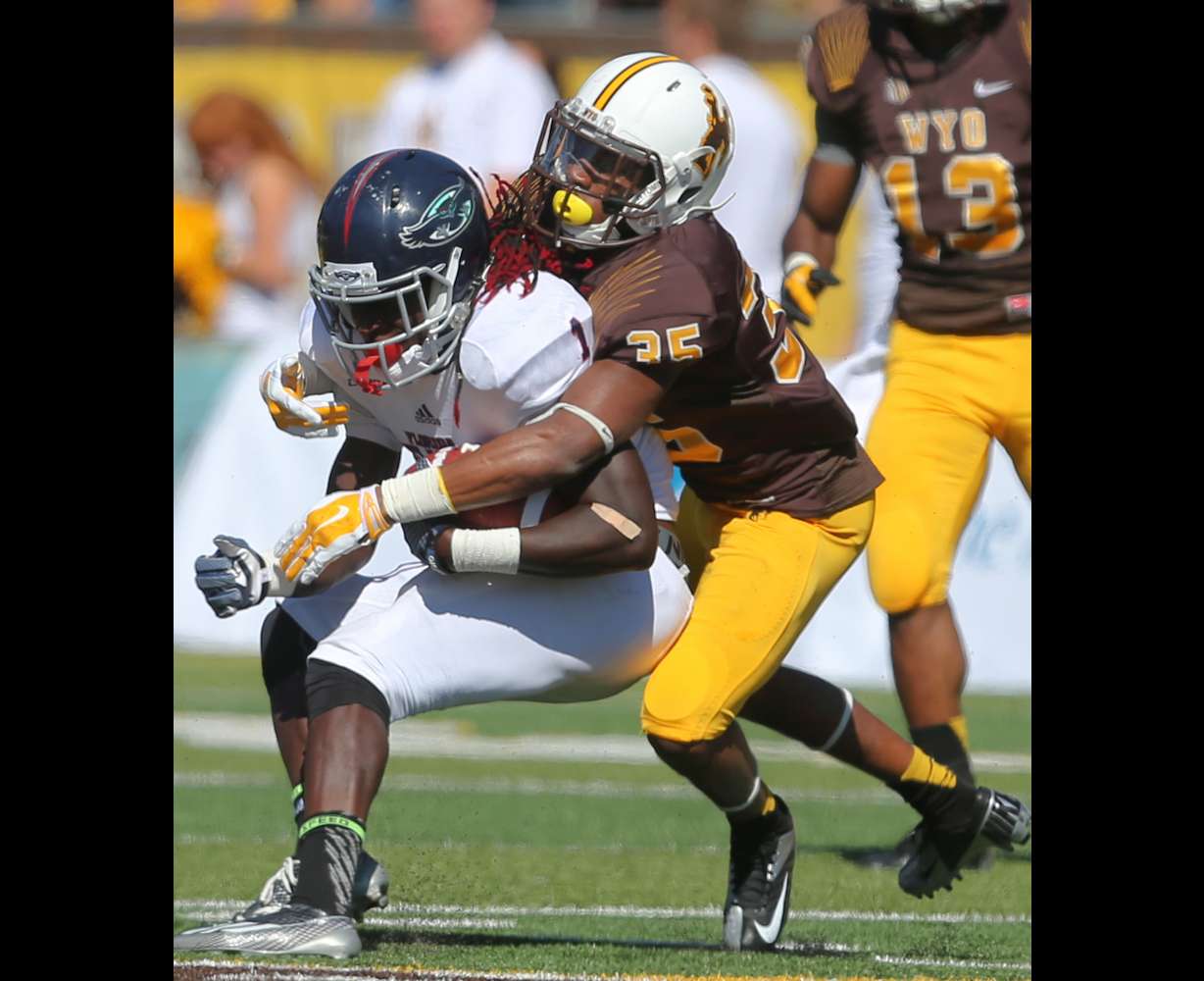 Florida Atlantic's Lucky Whitehead is tackled by Wyoming defender Robert Priester during the first half of an NCAA college football game Saturday, Sept. 20, 2014, in Laramie, Wyo.