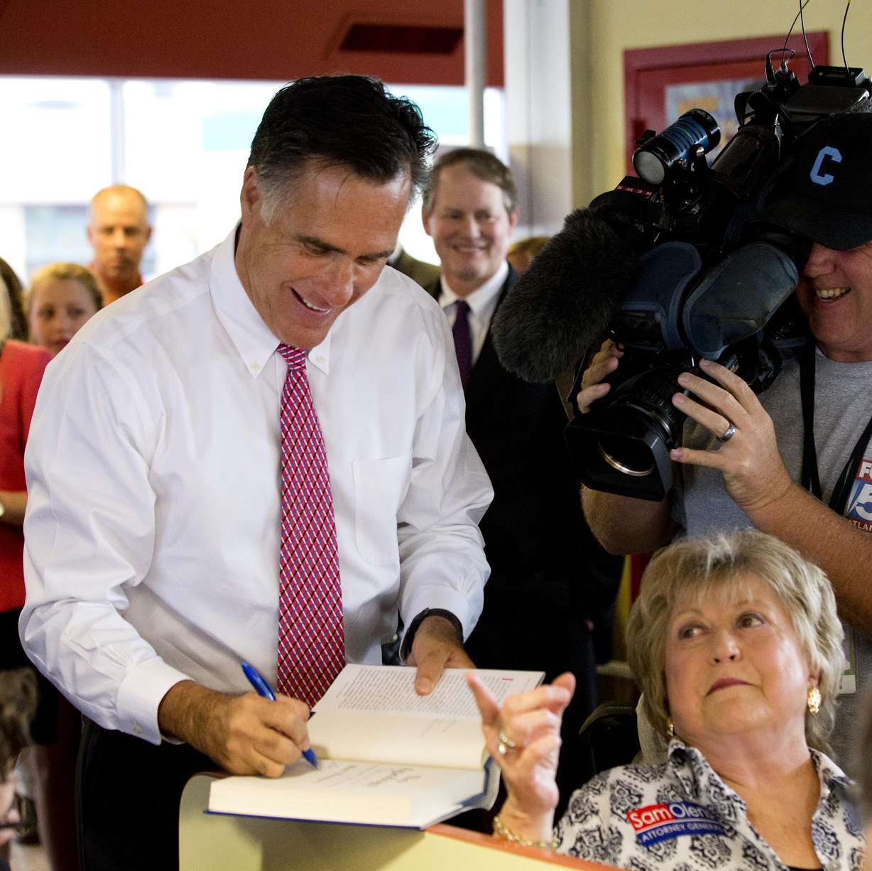 Former GOP presidential candidate Mitt Romney signs a book as he greets the lunch crowd at the Varsity, Wednesday, Oct. 1, 2014, in Atlanta.