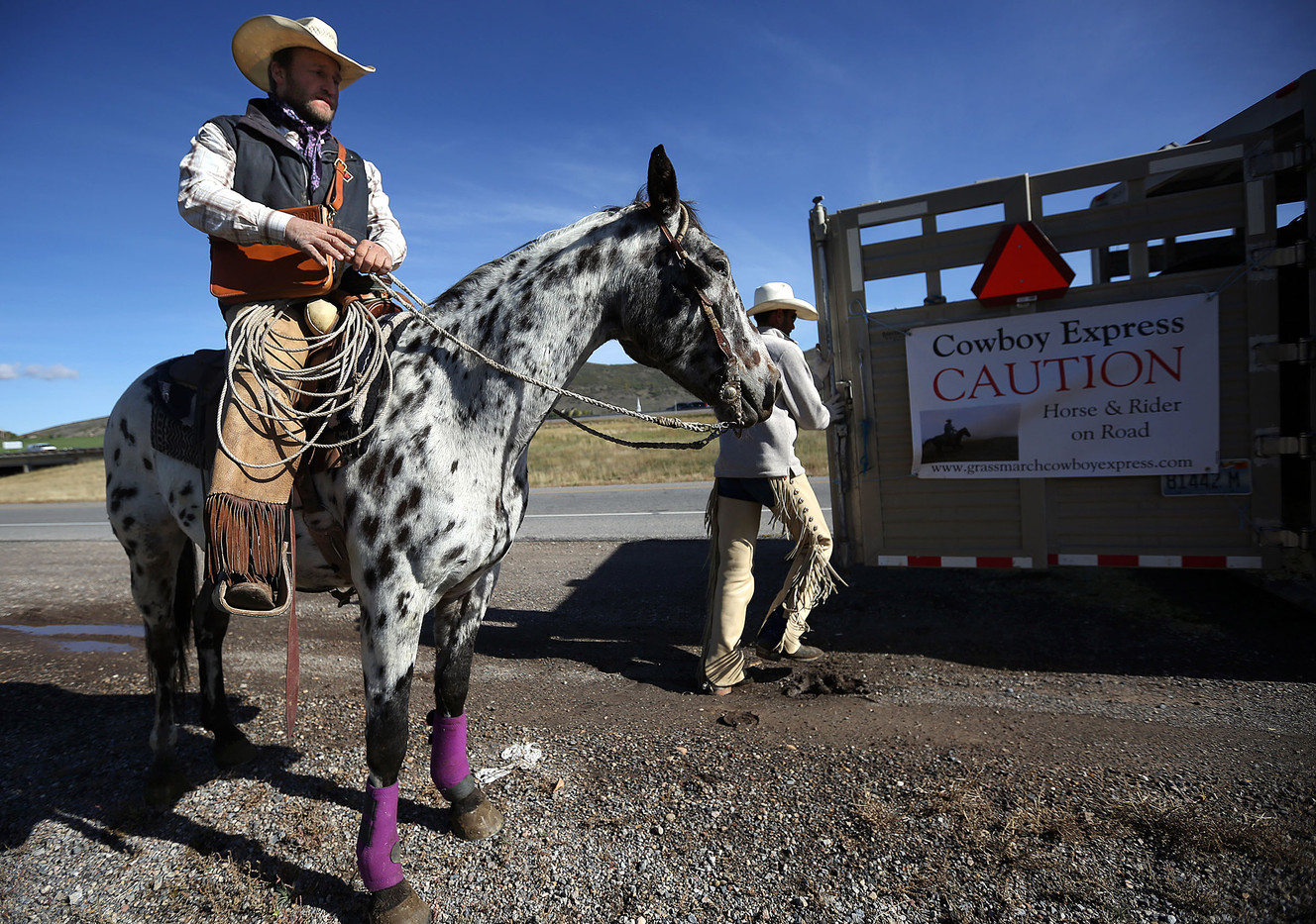 Jess Jones gets ready to ride Chief as Josh White puts another horse in the trailer at the the Jeremy Ranch exit of I-80 in Park City on Thursday, Oct. 2, 2014. The riders take turns driving or riding in the Grass March Cowboy Express. (Photo: Kristin Murphy, Kristin Murphy/Deseret News)
