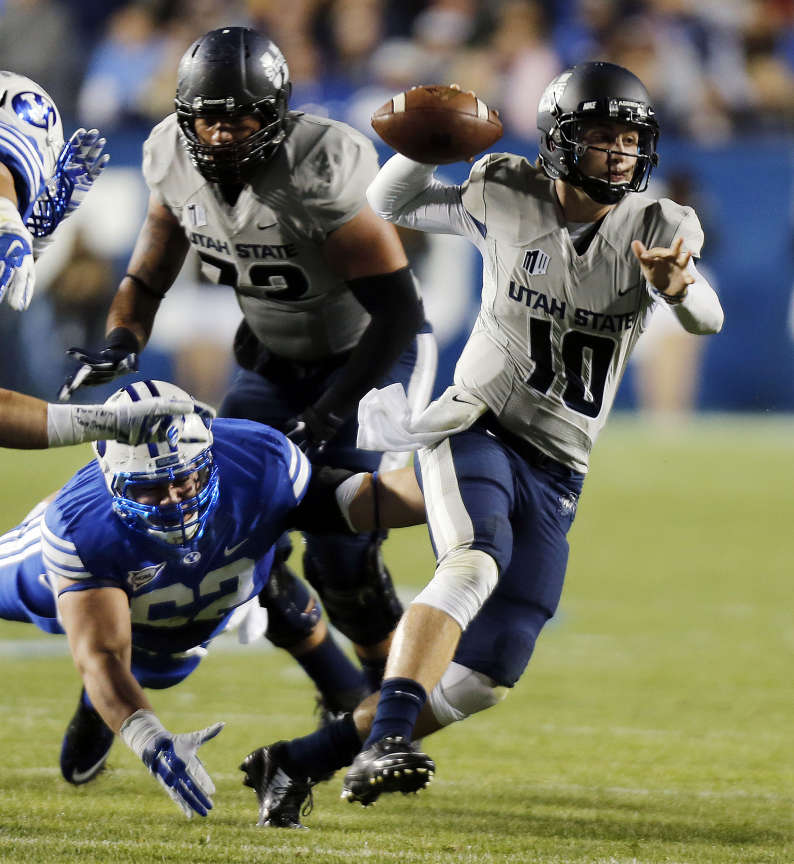Darell Garretson (10) of Utah State scrambles during an NCAA football game in Provo, Friday, Oct. 3, 2014. Diving is Logan Taele (62) of Brigham Young University. (Ravell Call/Deseret News)