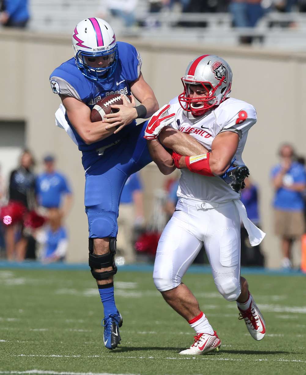 New Mexico defensive back David Guthrie, right, grabs the leg of Air Force quarterback Kale Pearson to make stop after short run in the first quarter of an NCAA college football game at Air Force Academy, Colo., on Saturday, Oct. 18. (AP Photo)