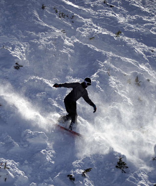 Snowboarder rides down a Brighton Ski Resort slope. Credit: Rick Bowmer, Associated Press.