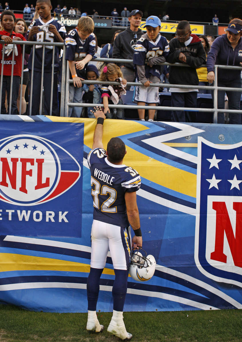 San Diego Chargers free safety Eric Weddle gives a memento to kids after the Chargers' game against the Buffalo Bills at a NFL football game Sunday, Dec. 11, 2011 in San Diego. (AP Photo/Lenny Ignelzi)