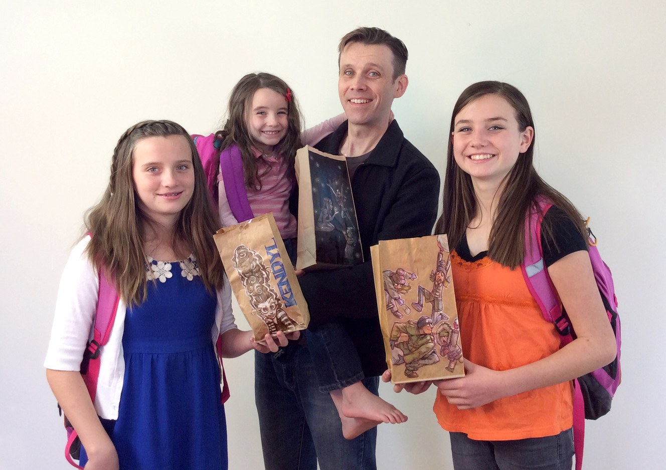 Seth Hippen poses with his three daughters and their newly drawn-on lunch bags. (Photo: Seth Hippen, http://whizbangbags.tumblr.com/)
