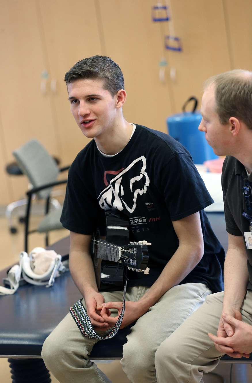 Joey Cottrell, left, and his occupational therapist Josh Parry speak to reporters about using a guitar as a way to strengthen Cottrell's fingers in the rehabilitation room at the Intermountain Medical Center in Murray on Friday, Dec. 19, 2014. Cottrell, from Centerville, was just five weeks into his LDS mission in England when a rare disease called Guillain-Barre syndrome sent him home in a wheelchair, barely able to move. He's now back on his feet and preparing to return to the mission field. (Photo: Laura Seitz, Deseret News)