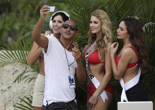 Un DJ posa con las aspirantes al Miss Universo Paulina Vega, de Colombia, a la izquierda, Gabriela Frankova, de la República Checa, e Ivana Misura, de Croatia, durante un desfile en traje de bajo el miércoles 14 de enero del 2015 en Doral, Florida. El certamen será el 25 de enero en Miami. (AP Foto/Lynne Sladky)