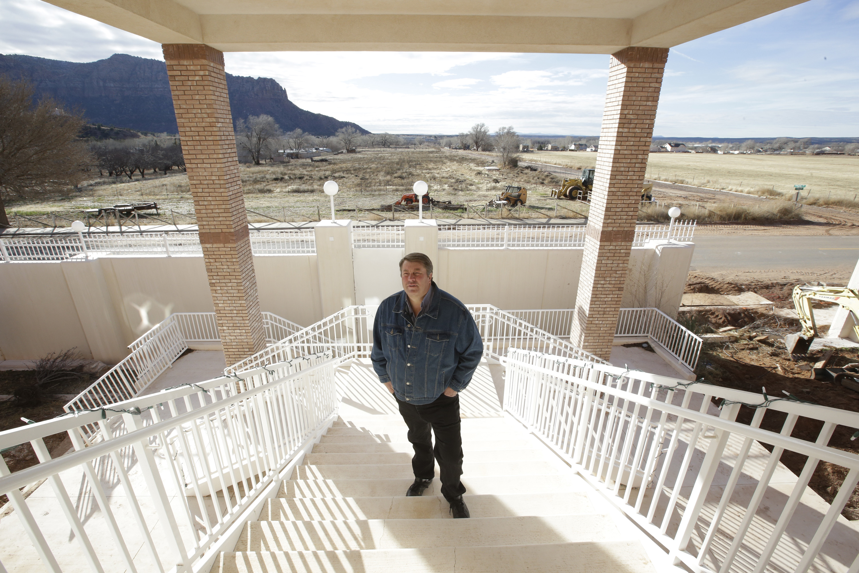 In this Dec. 16, 2014 photo, Willie Jessop, the former spokesman and bodyguard for the Fundamentalist Church of Jesus Christ of Latter-Day Saints, stands on the steps of a compound built for polygamist leader Warren Jeffs in Hildale, Utah. Jessop has converted the compound into a bed and breakfast. (AP Photo/Rick Bowmer)