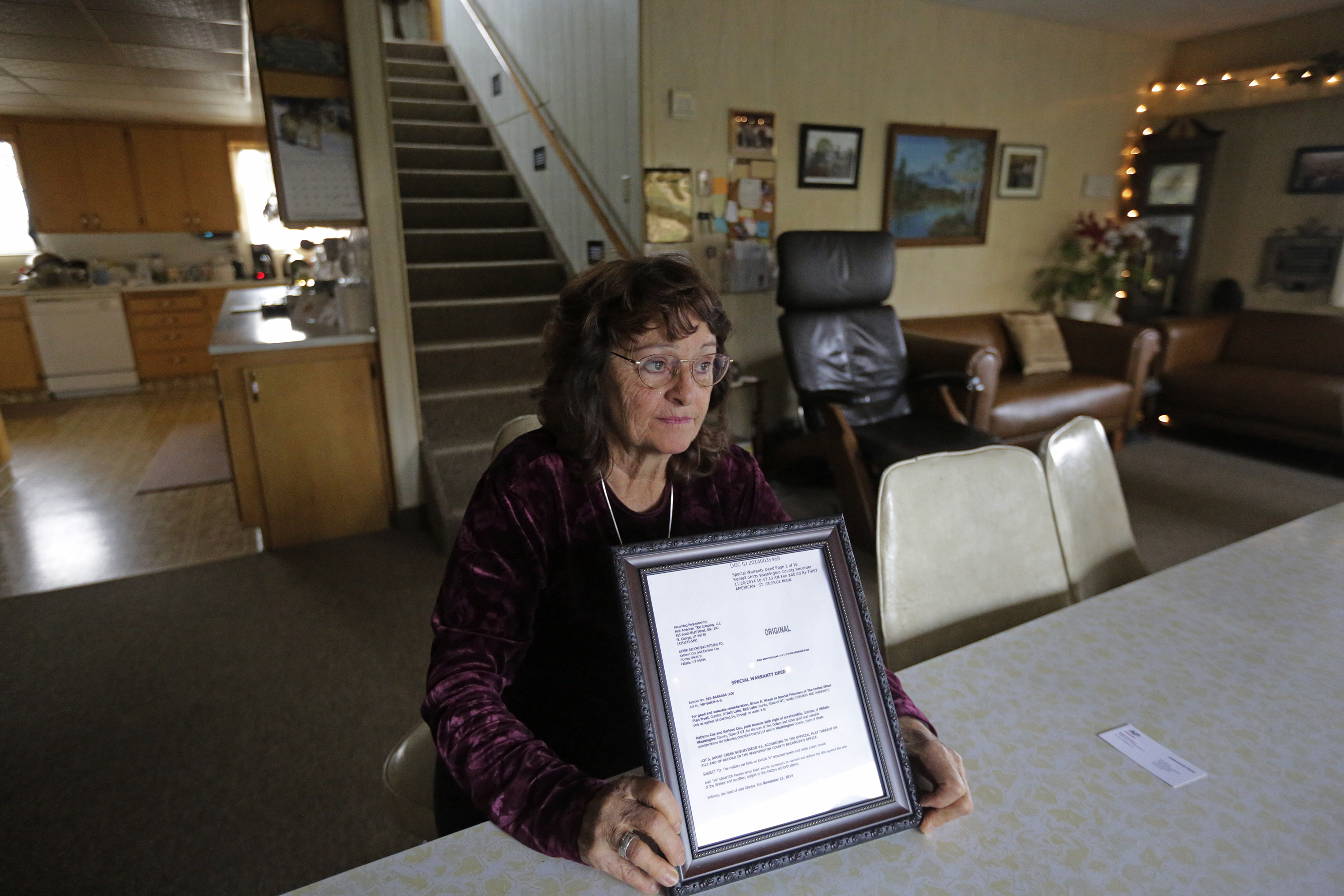 In this Dec. 16, 2014 photo, Katie Cox, a longtime Hildale, Utah, resident and member of the community's housing board, holds the framed deed to her house. She said granting home ownership has offered hope that sect leaders will be unable to control people by way of their houses... It's a symbol of freedom. It's a symbol that we are part of this United States." (AP Photo/Rick Bowmer)