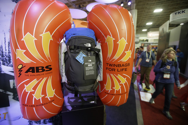 People walk past The North Face exhibit displaying its new avalanche airbag modulater system that is a set of dual air bags that can be attached to any backpack at the Outdoor Retailer Show Wednesday, Jan. 21, 2015, in Salt lake City. The theory is that skiers get used to their favorite packs and don't always want to use a new pack to have the air bag. (AP Photo/Rick Bowmer)
