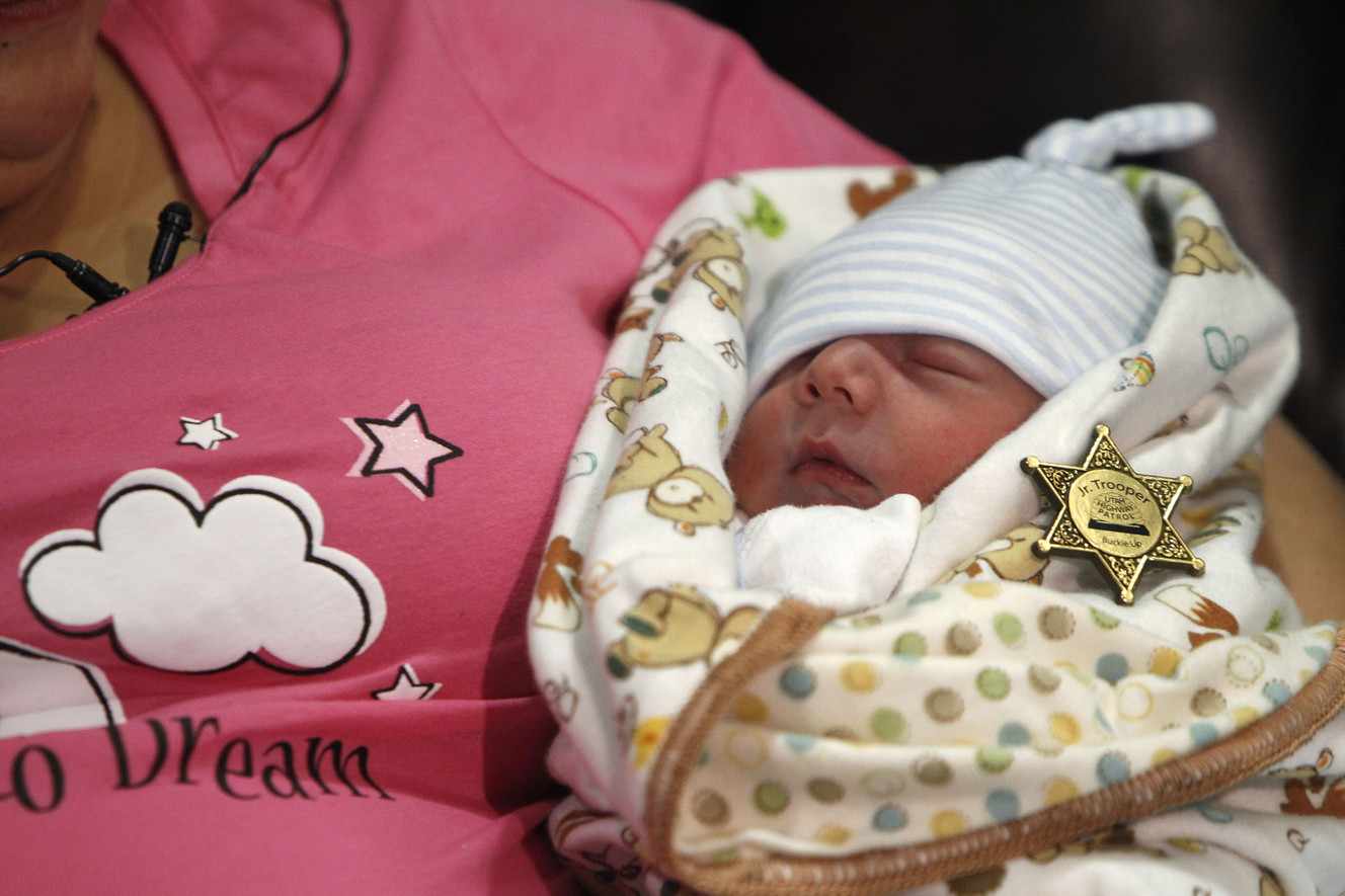 Utah Highway Patrol trooper Josh Carr gives a badge to Mariah Ostler's baby boy Sunday, Feb. 1, 2015.