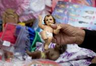 Una mujer sostiene una pequeña figura del niño Jesús mientras decide el vestido que habrá de comprarle en el mercado de La Merced, en la Ciudad de México, el 30 de enero de 2014, con vistas a la celebración católica del día de la Candelaria, el 2 de febrero. (AP Foto/Eduardo Verdugo)