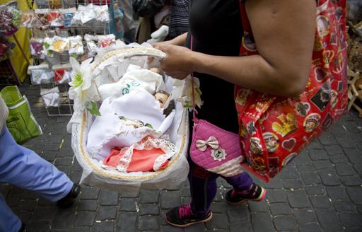 Una mujer carga una figura del niño Jesús en una canasta en el mercado de La Merced, en la Ciudad de México, el 30 de enero de 2015. Estas figuras son llevadas a bendecir en el día de la Virgen de la Candelaria, el 2 de febrero. (AP Foto/Eduardo Verdugo)