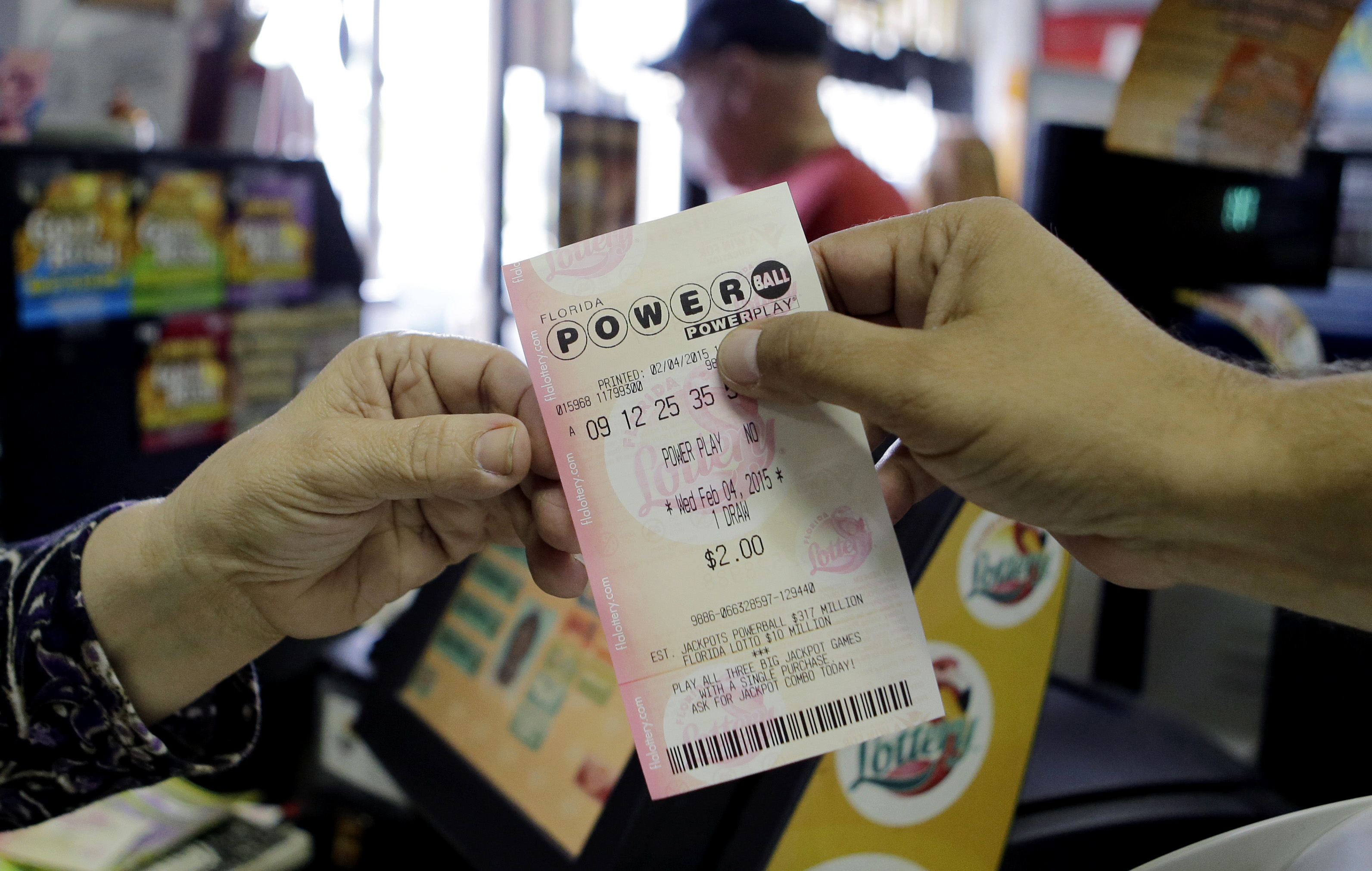 A store clerk hands a customer his Powerball ticket at a local grocery store in Hialeah, Fla., Feb. 4, 2015.