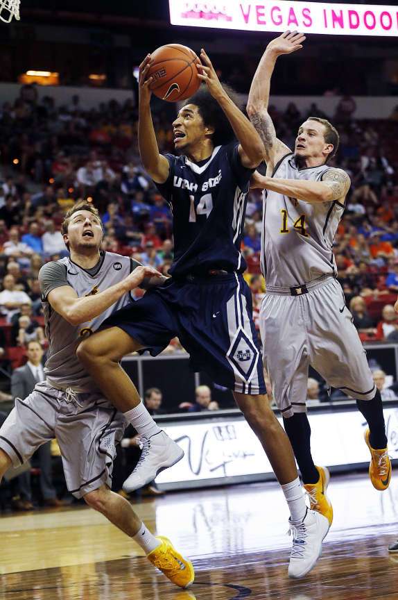 Jalen Moore (14) of the Utah State goes up for a shot with Josh Adams (14) and Riley Grabau (2) of Wyoming defending during a Mountain West tournament quarterfinal in Las Vegas, Thursday, March 12, 2015. (Ravell Call/Deseret News)