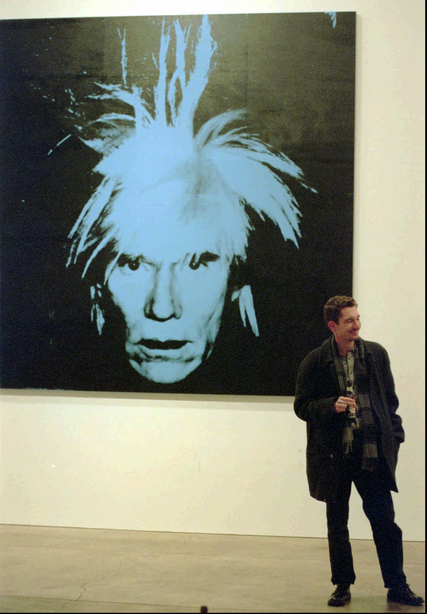 A patron at the Andy Warhol Museum on the North Side of Pittsburgh, Pa., enjoys a beer while standing under a Warhol self-portrait during Friday happy hour in the lobby of the museum, Feb. 4, 2000. The weekly happy hours are just one of the diverse attractions beyond the Warhol works on display that museum director Thomas Sokolowski is doing to attract people and keep the museum on the edge. (AP Photo/Keith Srakocic)