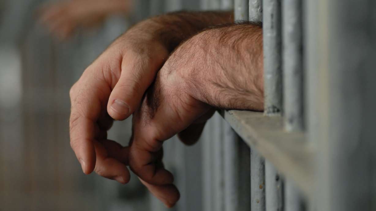 man hands behind bars in jail prison