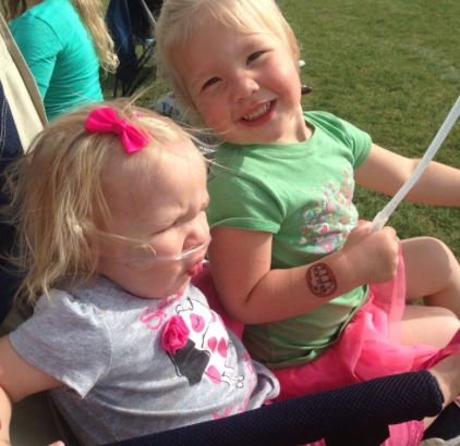 MayLee (left) pictured with sister, Eden (right). MayLee was born with a respiratory issue that requires her to breath from a tube all day and all night. (Photo: Brynn Homer)