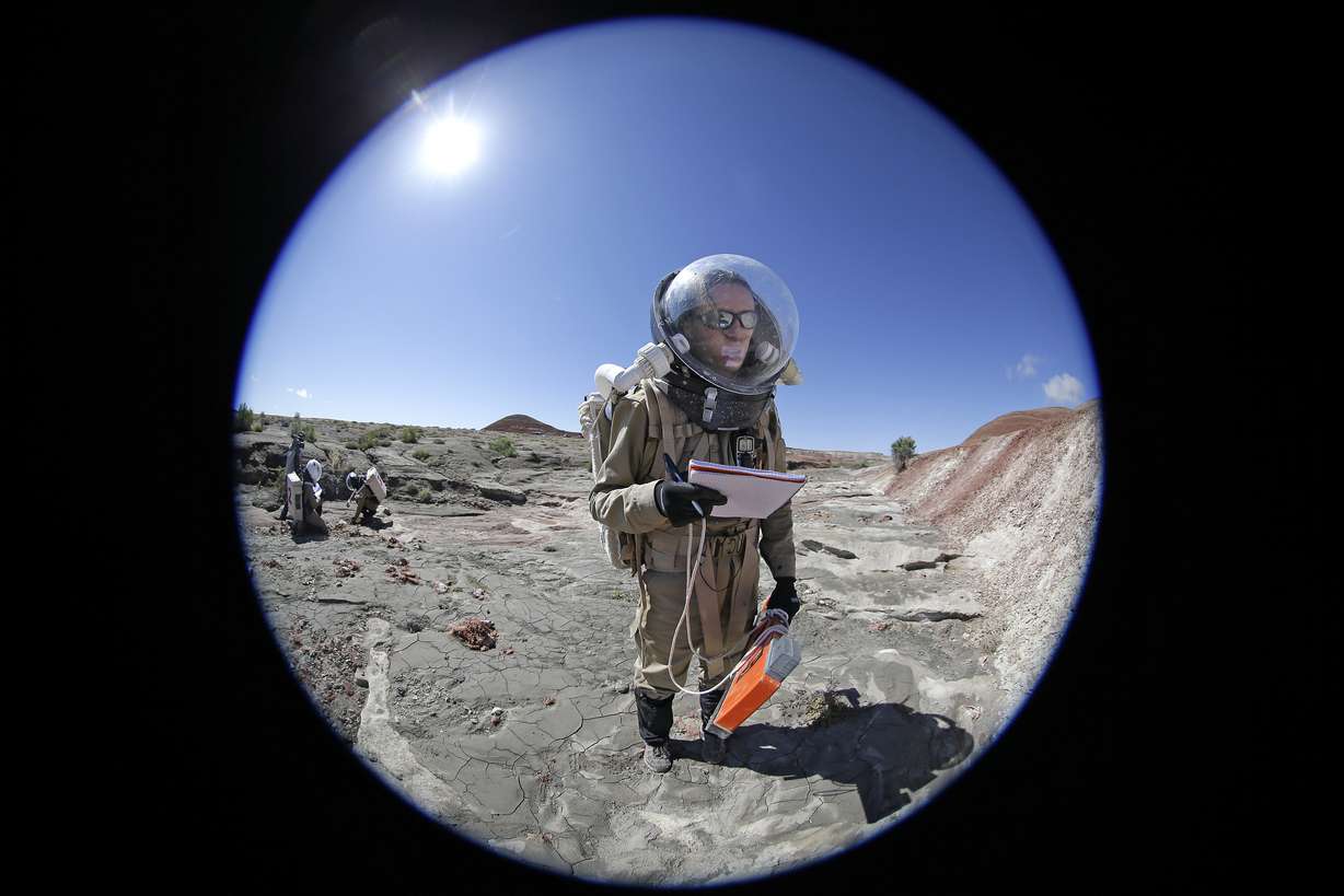 In this photo taken on Saturday, April 18, 2015, Auriane Canesse, crew geologist and health and safety officer, of Crew 153, takes magnetic readings of the ground using a large rectangular apparatus near the Mars Desert Research Station, in Hanksville, Utah. This isn't Mars, but it's resemblance to the red planet has made it a hot spot for teams of geologists, biologists and engineers from around the world who have been coming for more than a decade to simulate missions to the mysterious planet in hopes of providing critical research to for future trips to Mars. (AP Photo/Rick Bowmer)