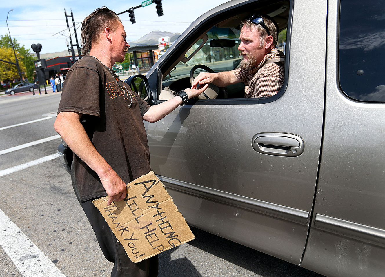 Jessie Cone, left, accepts loose change from a stranger in Salt Lake City on Friday, May 1, 2015. A Utah Policy poll finds 2/3 of Salt Lake City residents think panhandling should be illegal. Cone believes that there would be a rise in shoplifting if panhandling becomes fully illegal. (Photo: Laura Seitz, Deseret News)
