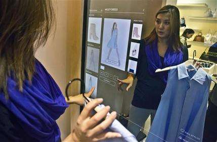 In this April 10, 2015 photo, Christie McAllister, visiting from San Francisco, prepares to use a fitting room equipped with eBay's touch screen fitting room technology, at Rebecca Minkoff in New York. The interactive technology provides a virtual assistant inside fitting rooms for shoppers, displaying their selections and a catalog to modify choices and accessorize. (AP Photo/Bebeto Matthews)