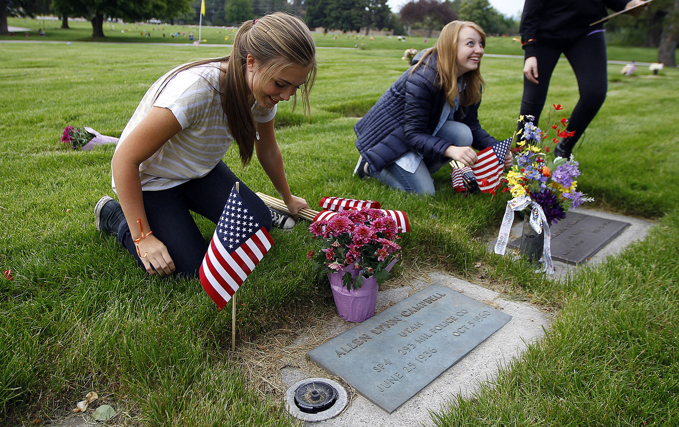Makayla Jones, left, and Cedi Christensen place American flags at the graves of veterans at the Larkin Sunset Gardens Cemetery in Sandy on Thursday, May 21, 2015. Photo: Chris Samuels, Deseret News