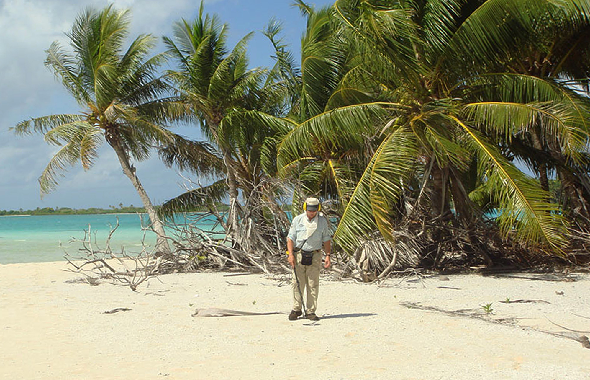 In this undated photo provided by The International Group for Historic Aircraft Recovery in June 2015, Ric Gillespie, the group's co-founder, stands on a beach during an expedition to the South Pacific island of Nikumaroro in Kiribati. Gillespie and TIGHAR team members have made several trips to the island in search of any sign of Amelia Earhart and her navigator, Fred Noonan. So far, nothing can be proven - but he says several of artifacts they've found are from the right era. (TIGHAR via AP)